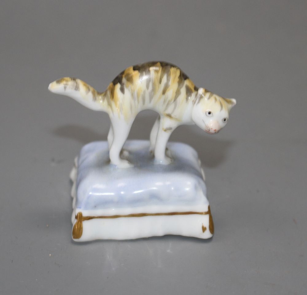 A rare Staffordshire toy porcelain figure of a cat with arched back, on a cushion, c.1835-50, H. 4.6cm